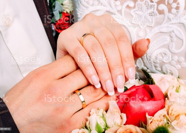 Newly married couple holding hands together wearing wedding rings with beautiful bridal manicure